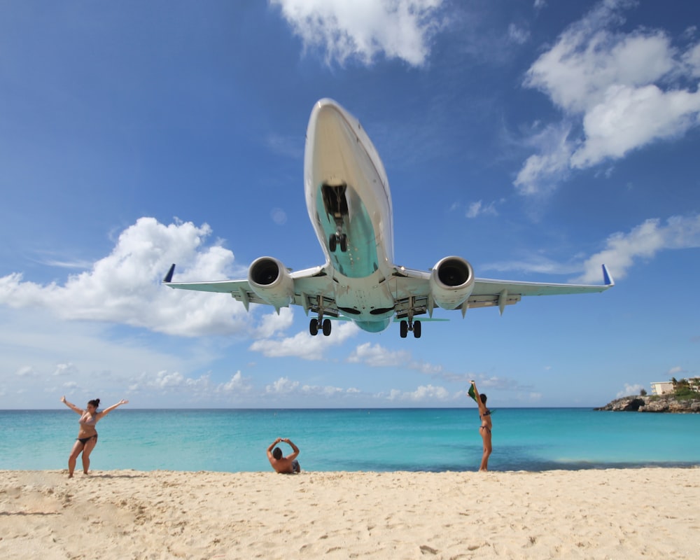 white airplane on white sand near body of water during daytime