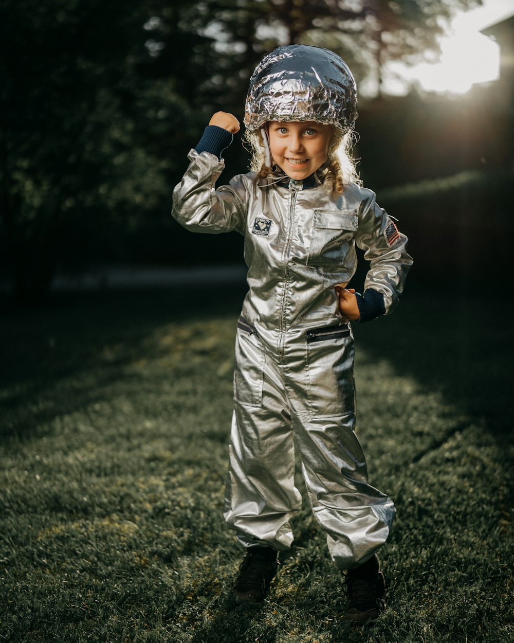 child in gray jacket and pants standing on green grass field during daytime