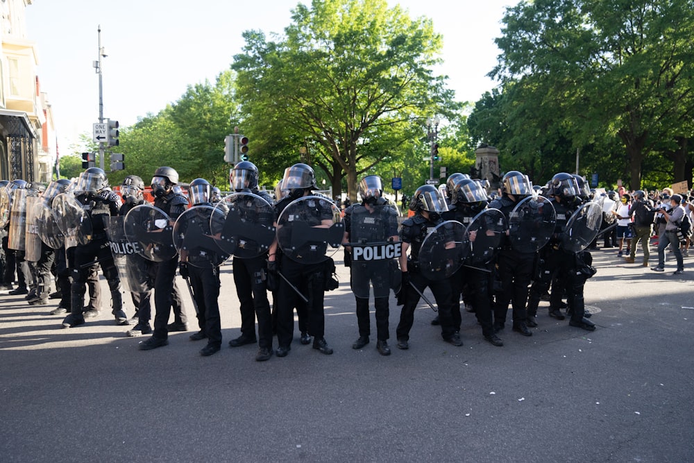 men in black and white uniform standing on road during daytime