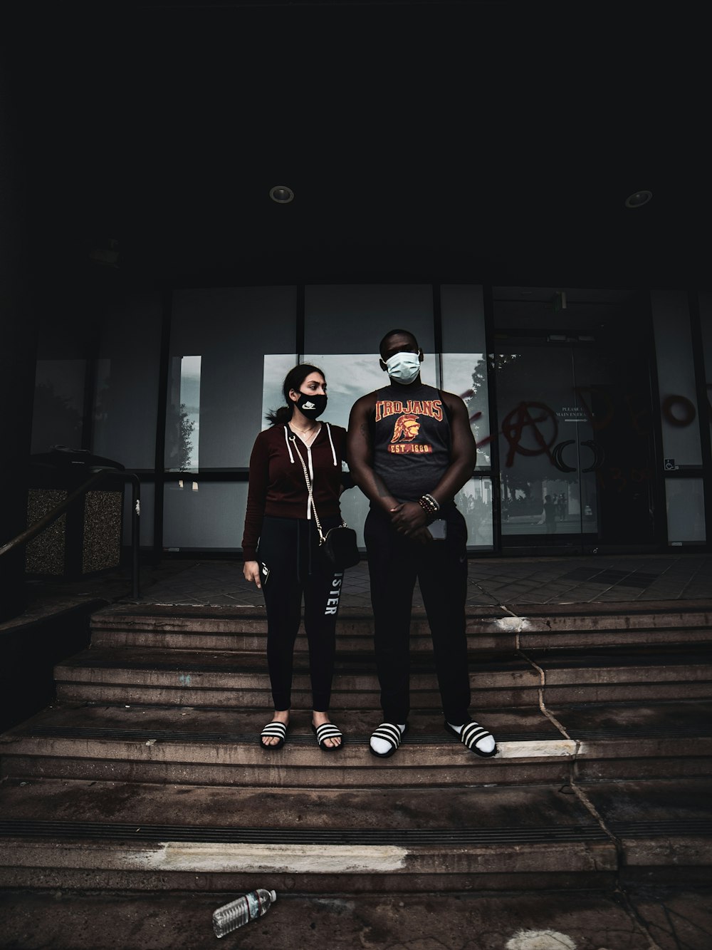 man in black crew neck t-shirt and black pants standing on brown wooden staircase