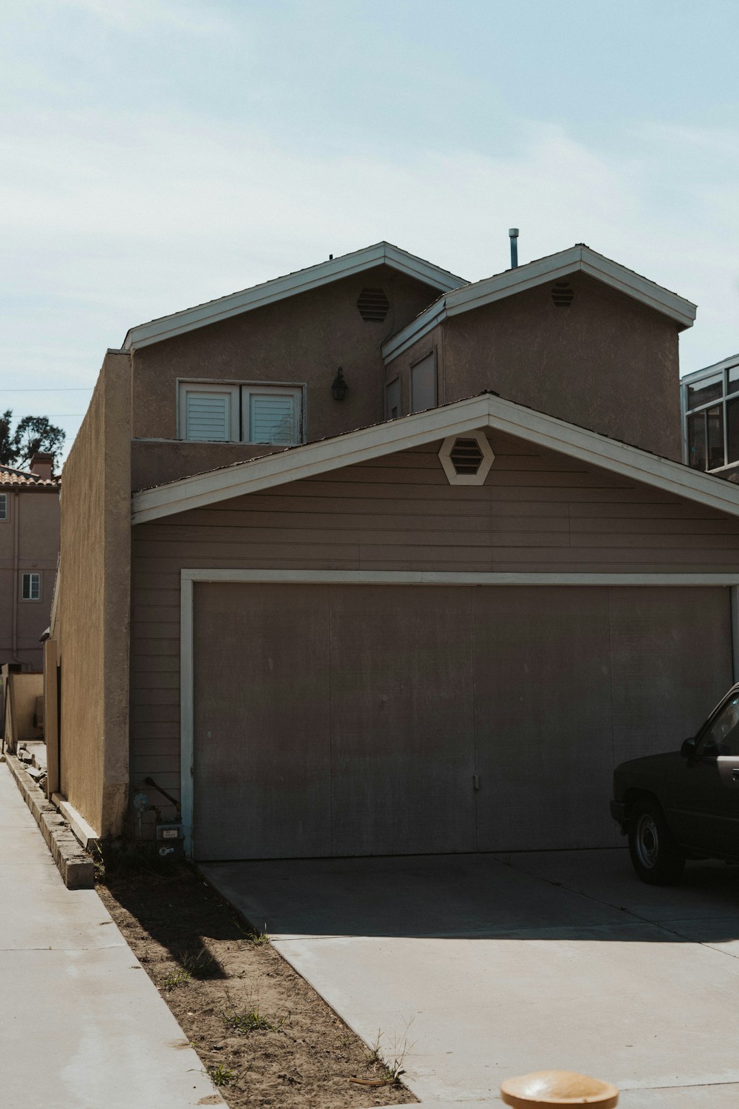 black car parked beside brown wooden house during daytime