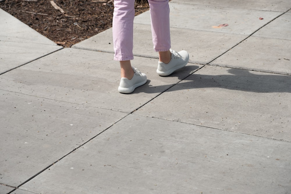pessoa em calças cor-de-rosa e tênis brancos
