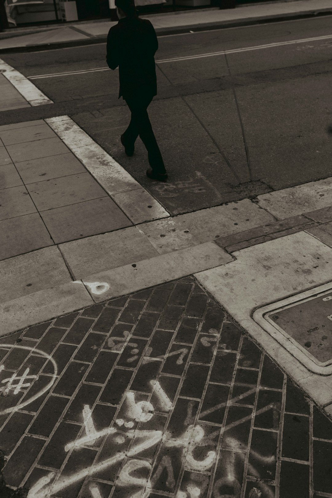 person in black pants walking on sidewalk during daytime