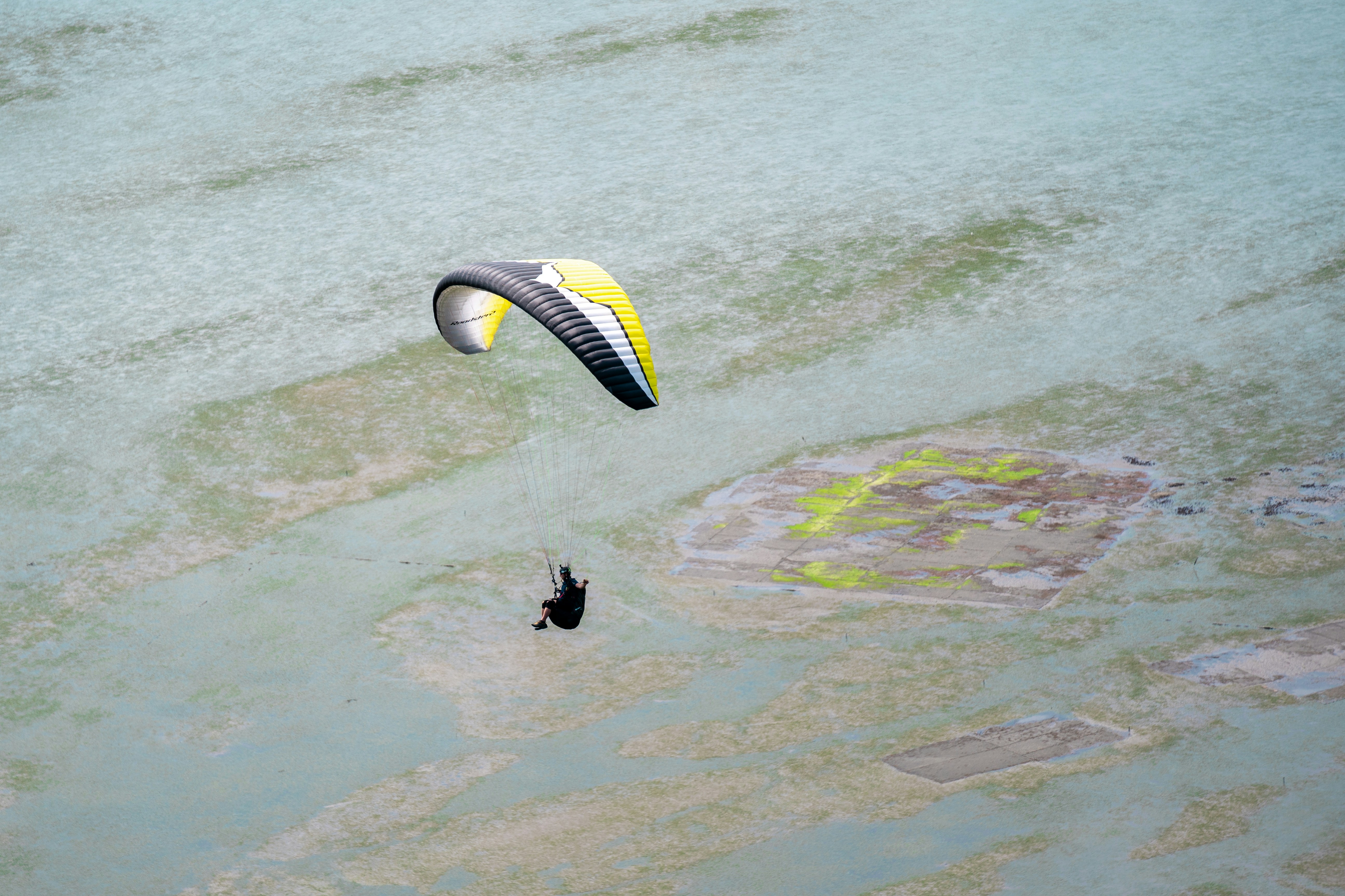 person riding on yellow and white parachute