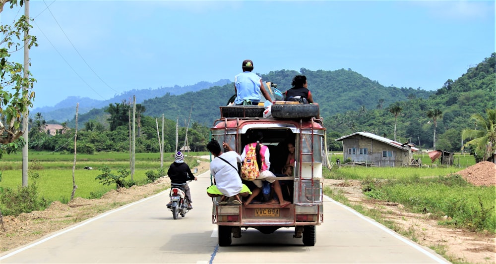 man in blue shirt riding on red and black auto rickshaw during daytime