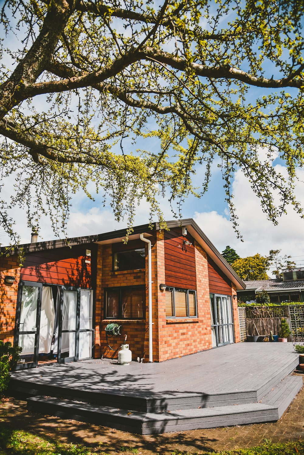 brown wooden house near green tree during daytime