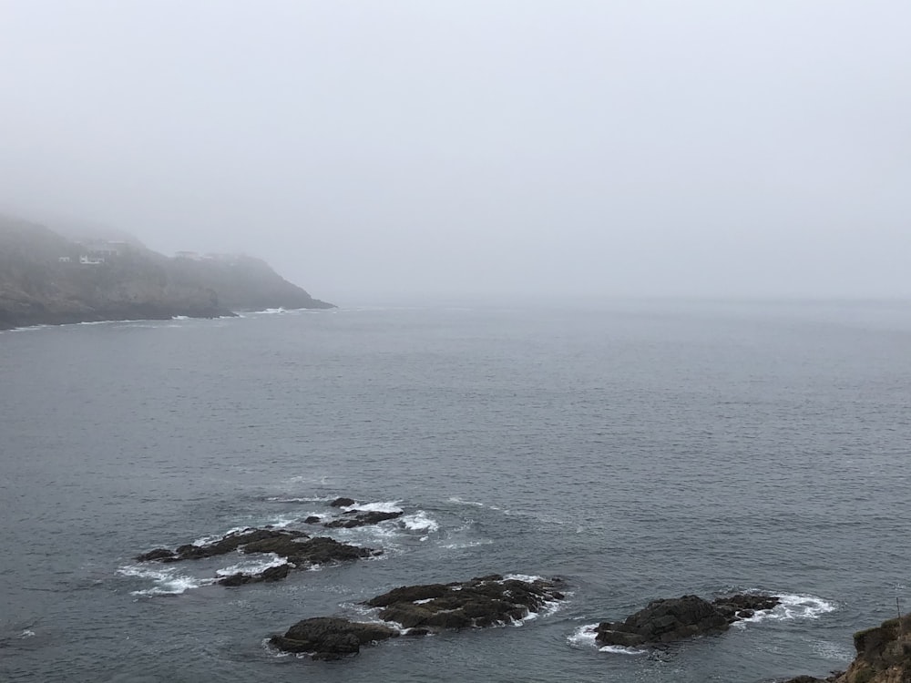 black rock formation on sea during daytime