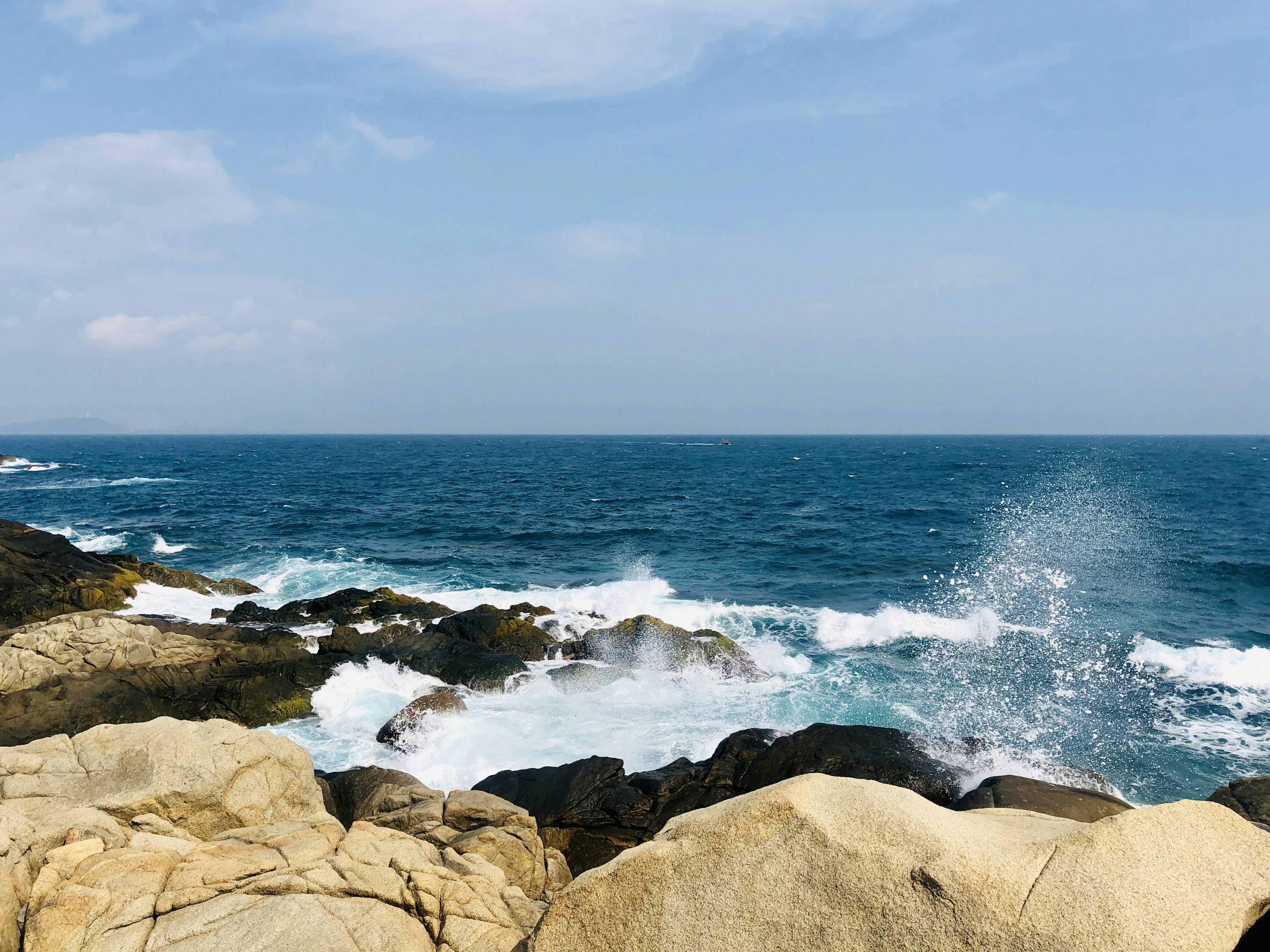 brown rocky shore near body of water under white cloudy sky during daytime