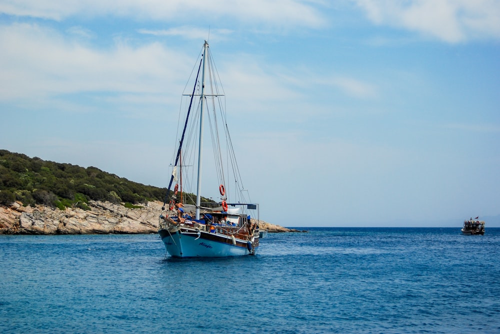 brown and white boat on sea under white clouds during daytime