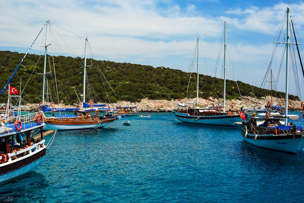 MG TURIZM A blue and white boat on sea near green mountain under blue sky during daytime
