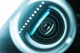 A close-up of a futuristic industrial camera lens reflecting complex machinery and data streams.