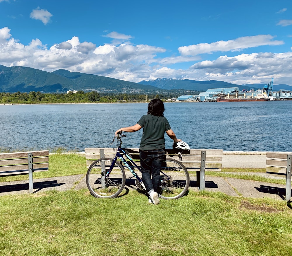 man in black shirt riding bicycle near body of water during daytime