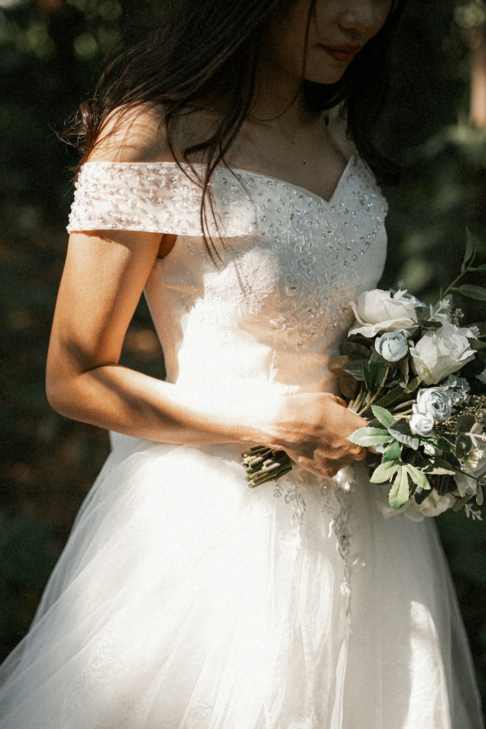 woman in white floral dress holding white flower bouquet