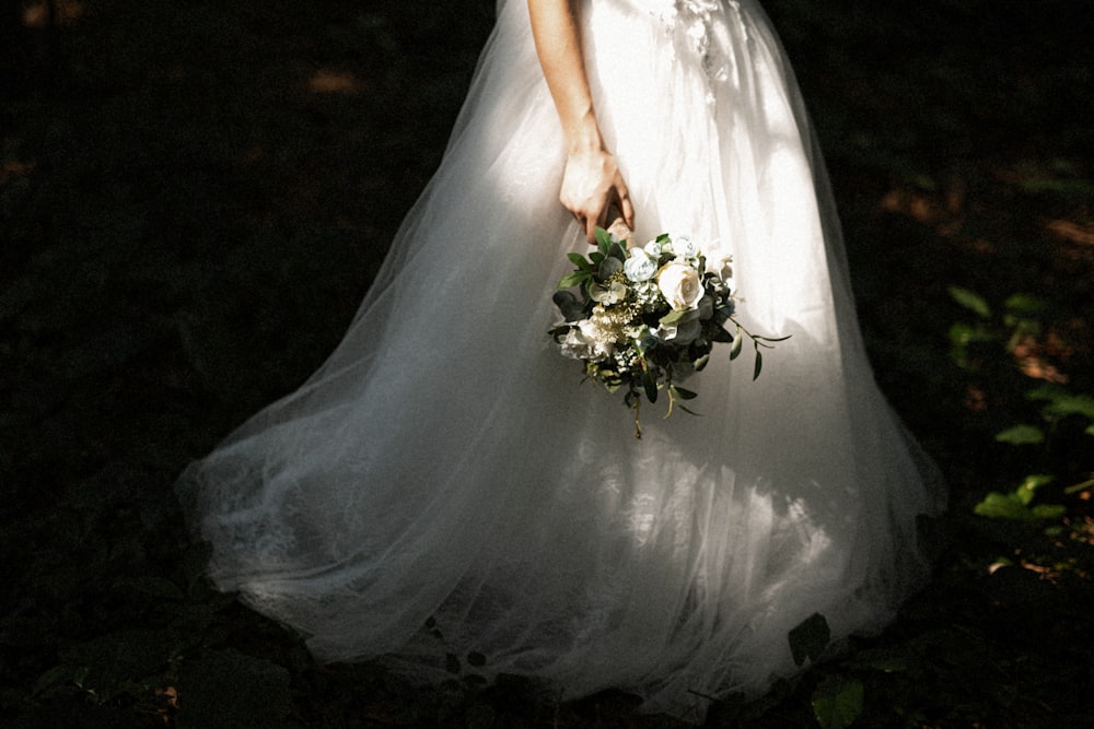 woman in white wedding dress holding bouquet of flowers