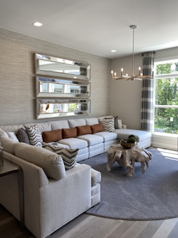 A modern living room featuring a large decorative wall mirror reflecting natural light.