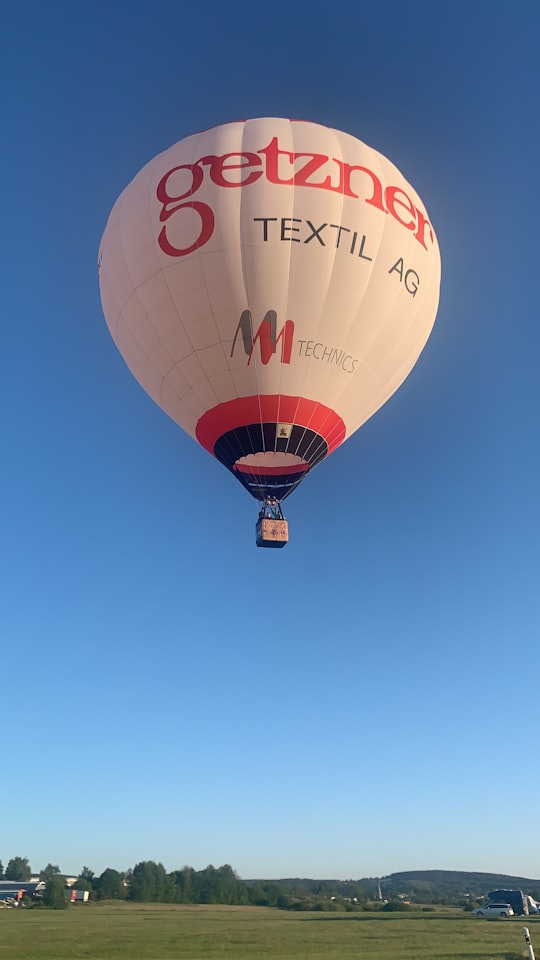 red and white hot air balloon in mid air under blue sky during daytime in Zeppelinstraße 2 Germany