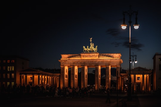 people walking on street near building during night time in Brandenburg Gate Germany