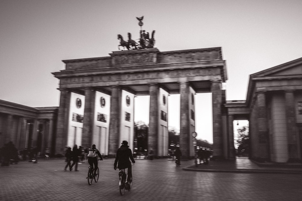 Graustufenfoto von Menschen, die in der Nähe des Gebäudes spazieren gehen