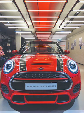 A bold red sports car gleaming under bright showroom lights, inviting a closer look.