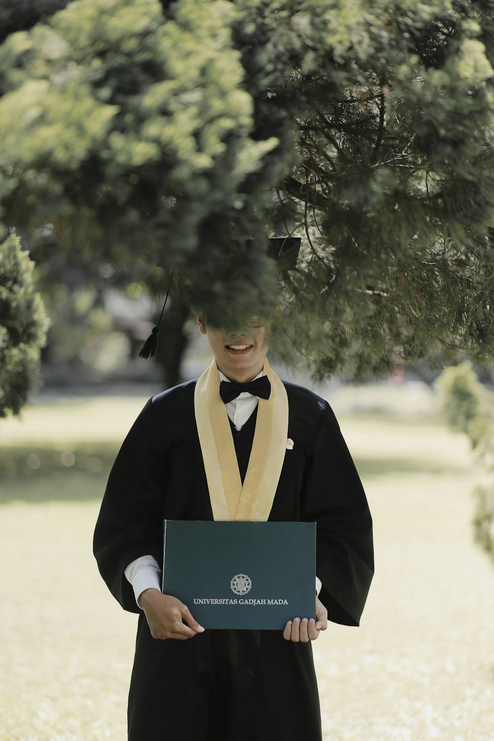 hombre en toga académica negra sosteniendo papel azul