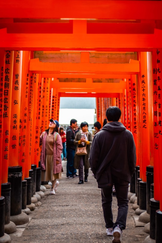 man in black jacket standing in front of people in Fushimi Inari Taisha Shrine Senbontorii Japan