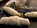 Rectangular pastry strips stacked beside a rolling pin on a marble countertop.
