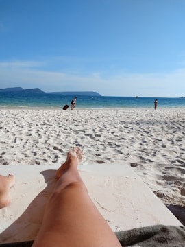 An influencer lounging on a golden sandy beach with turquoise waves in the background.
