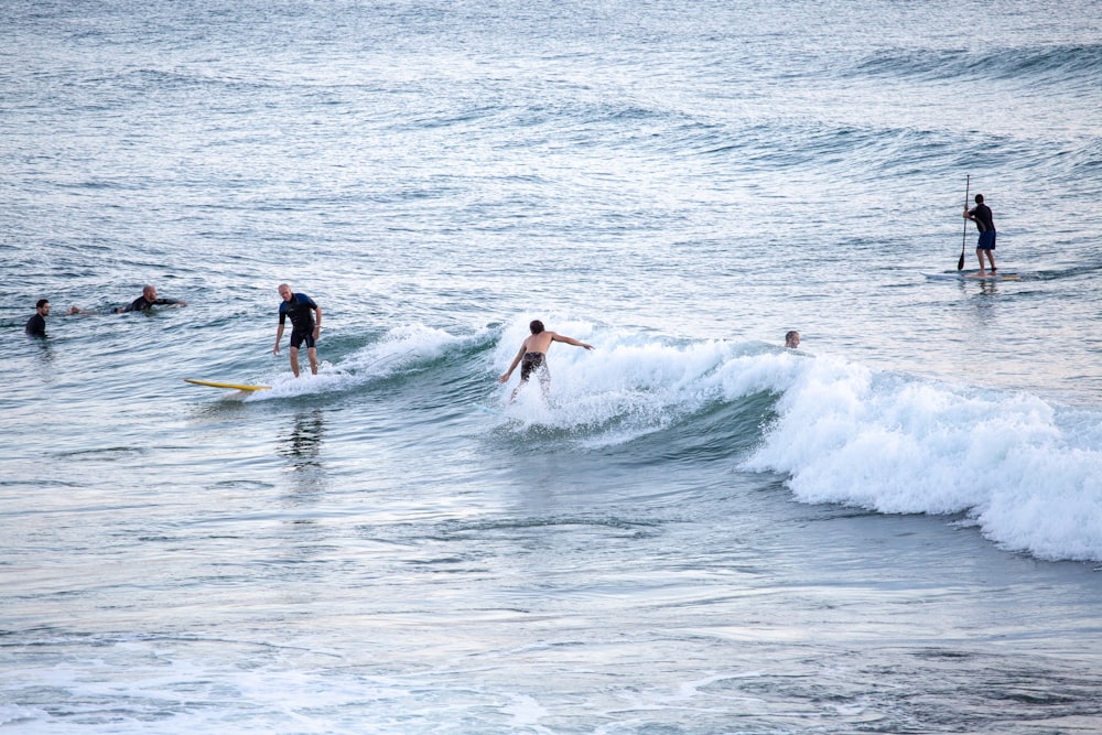 2 men surfing on sea waves during daytime