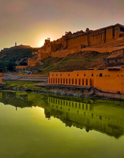 A panoramic view of a grand fort bathed in golden sunset light, with traditional Indian architecture.