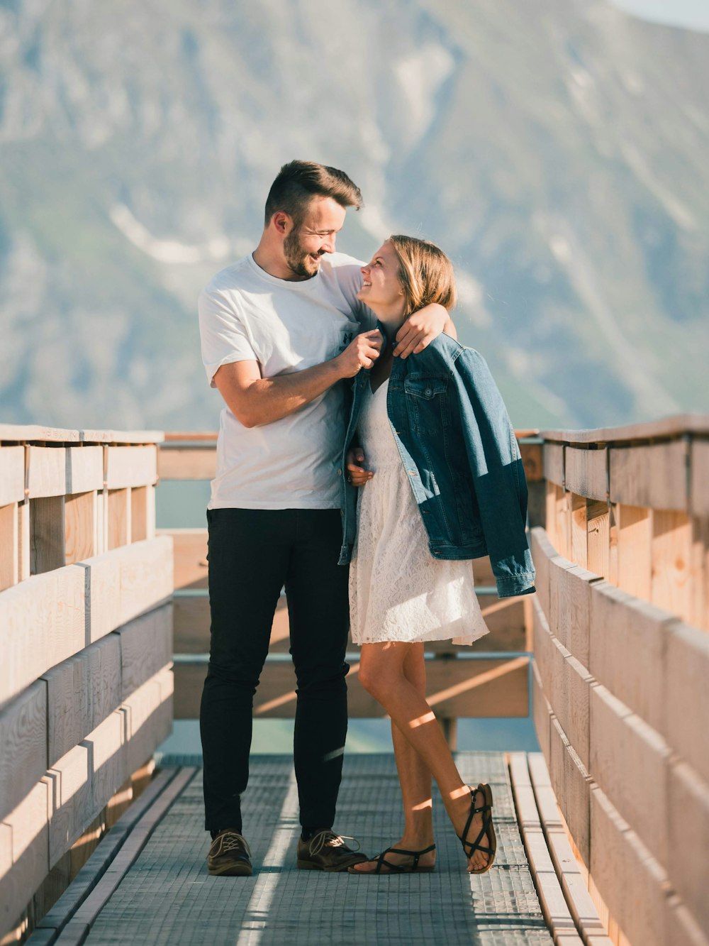 man in white t-shirt and black pants hugging woman in blue dress