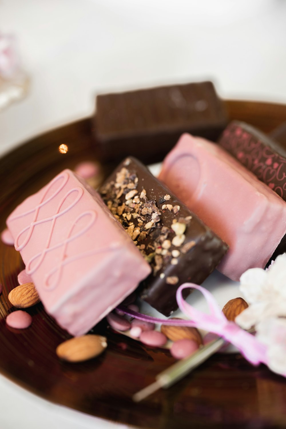 Tavoletta di cioccolato rosa e marrone su piatto rotondo di legno marrone