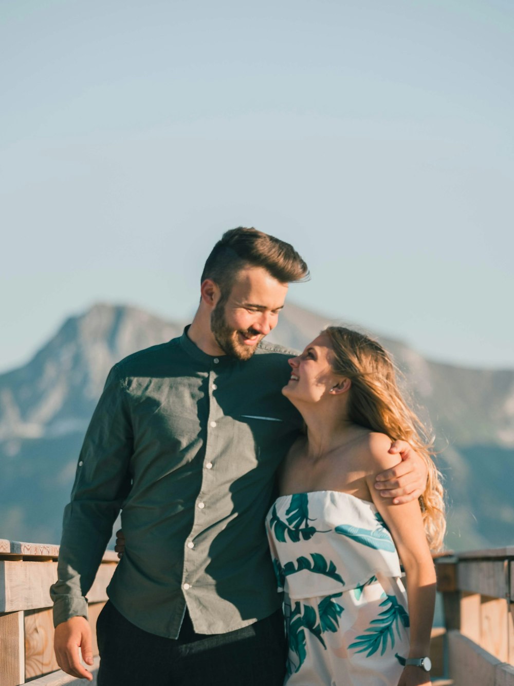 man in black jacket kissing woman in white and blue floral tank top during daytime