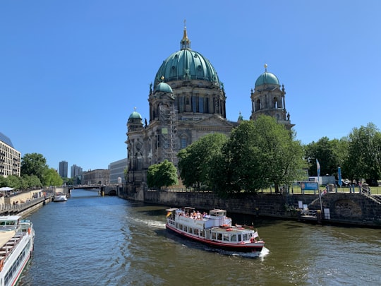 white and red boat on water near white and gray concrete building during daytime in Berlin Cathedral Germany
