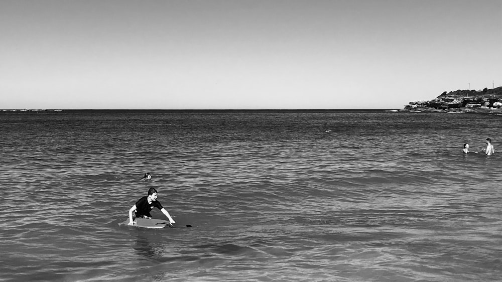 grayscale photo of man surfing on sea