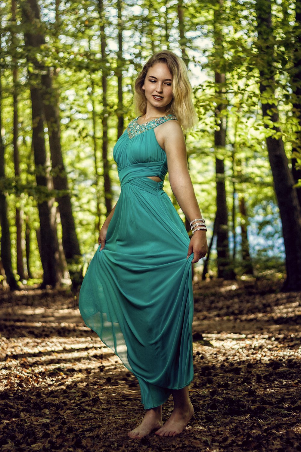 woman in green sleeveless dress standing on forest during daytime