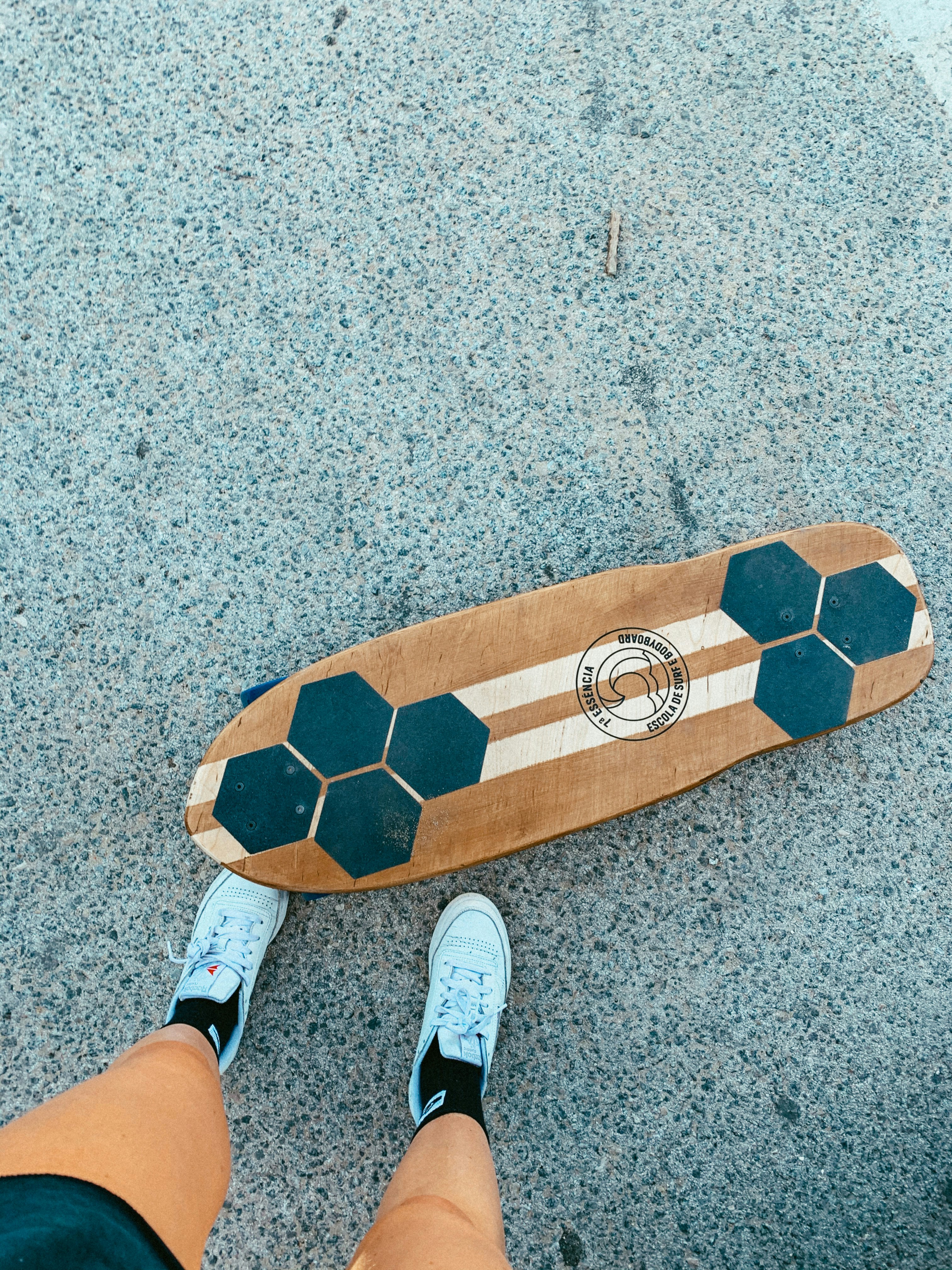 person wearing white socks standing on brown and beige surfboard
