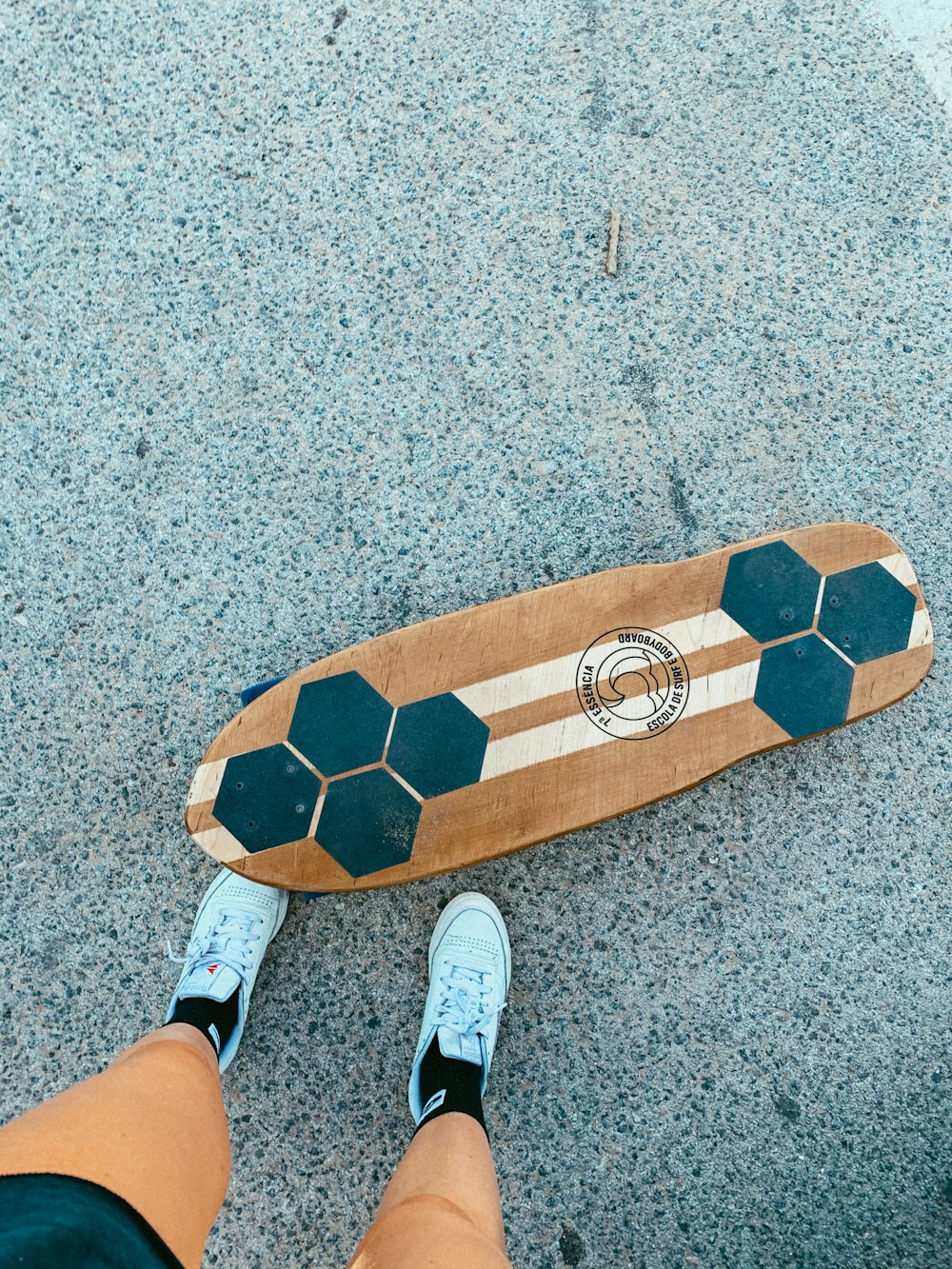 person wearing white socks standing on brown and beige surfboard