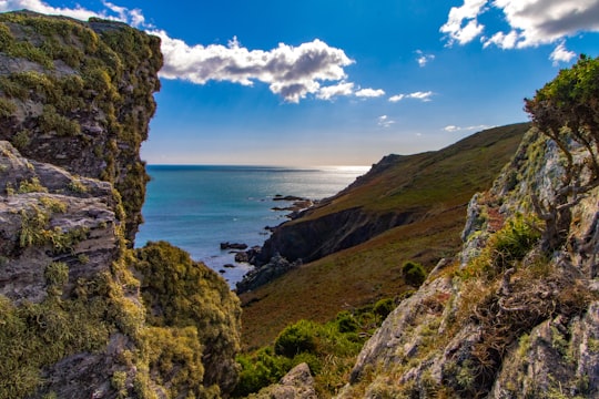 green and brown mountain beside sea under blue sky and white clouds during daytime in South Devon Area Of Outstanding Natural Beauty (AONB) United Kingdom