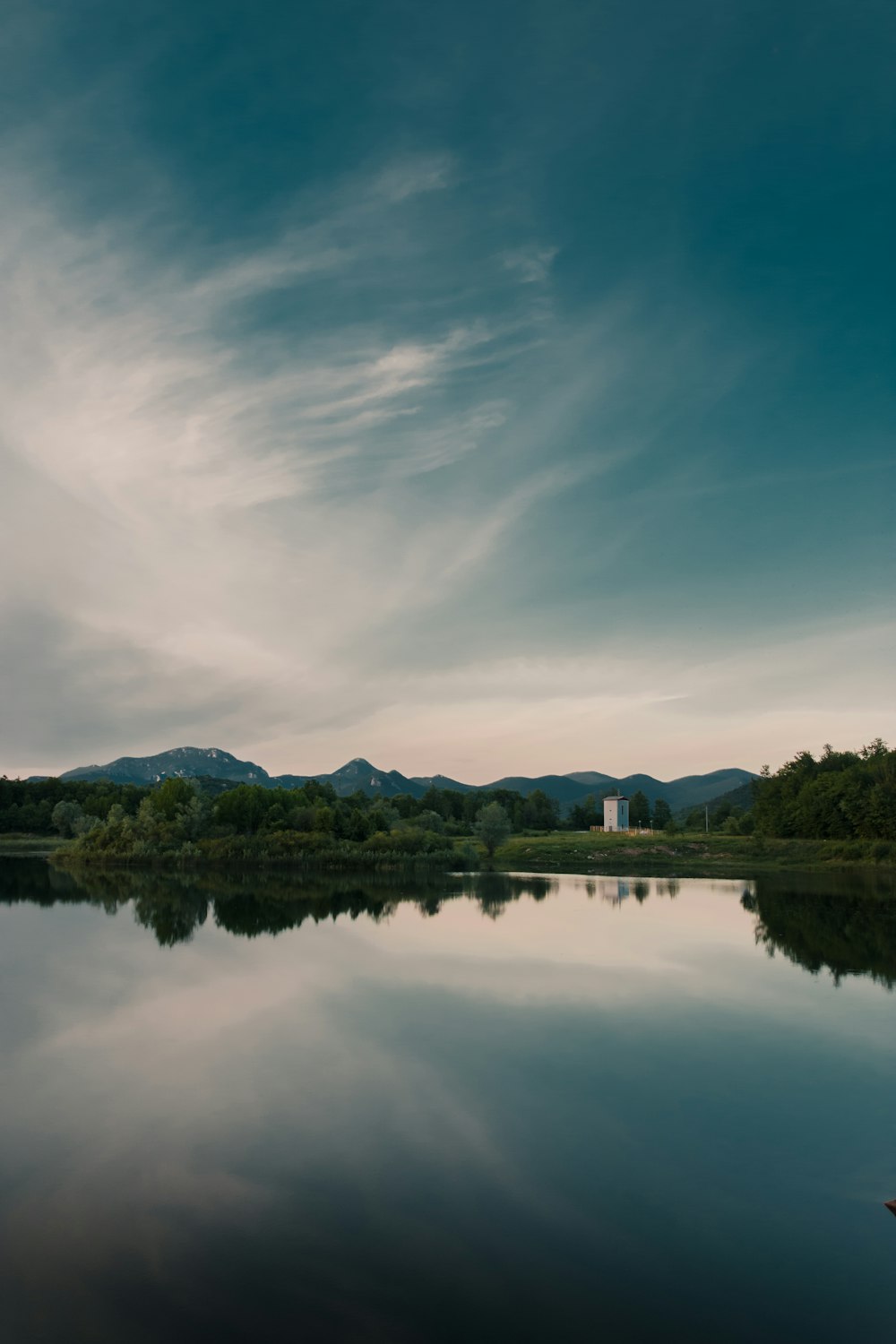 green trees near lake under blue sky during daytime