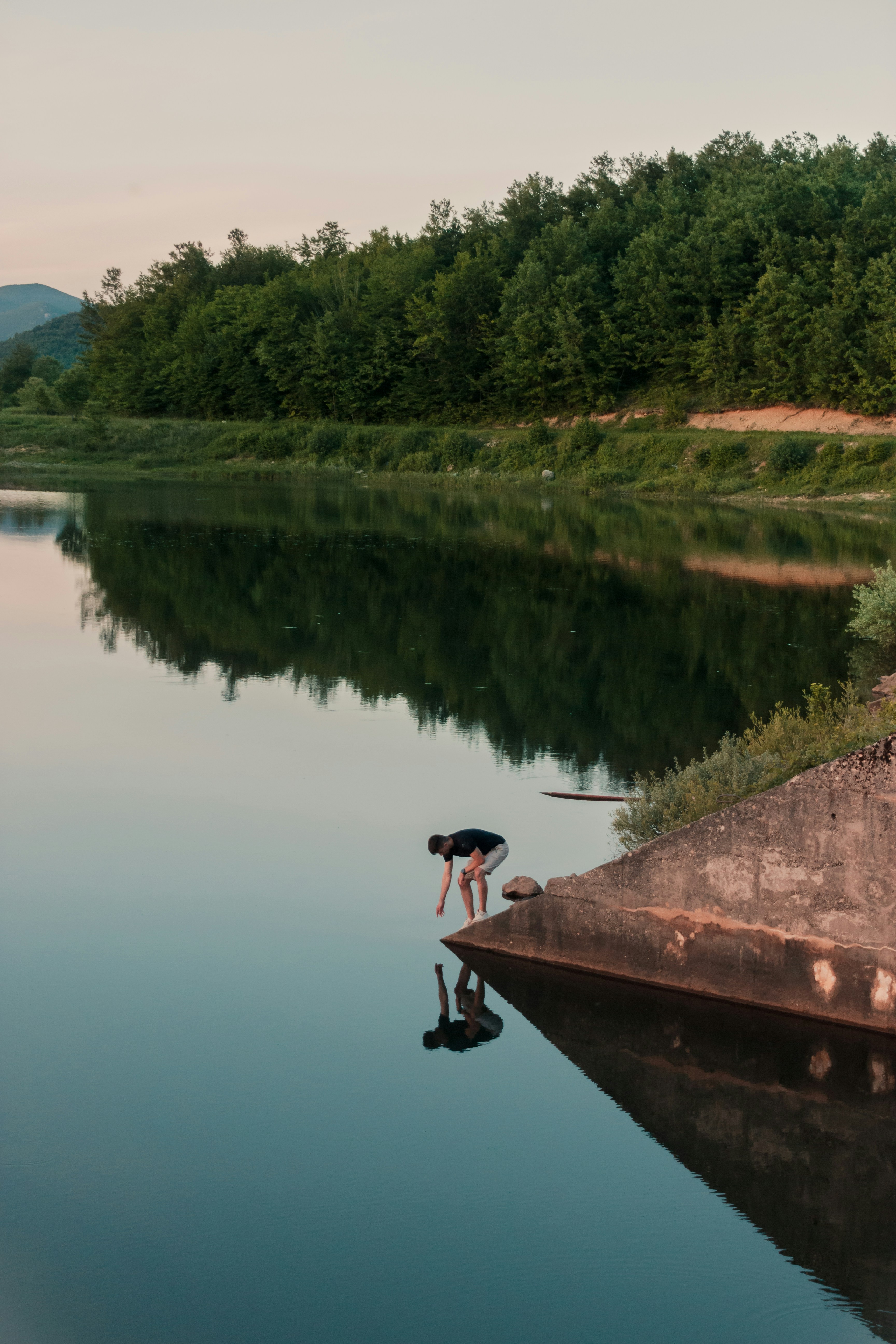 person standing on dock near lake during daytime