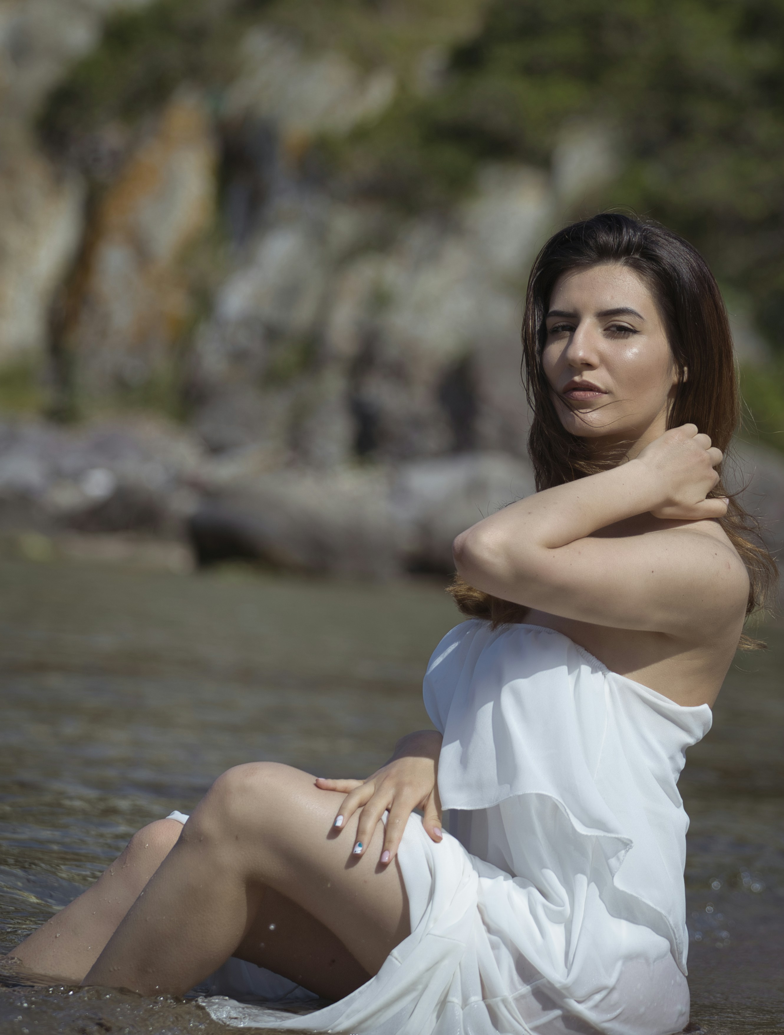 woman in white dress sitting on rock