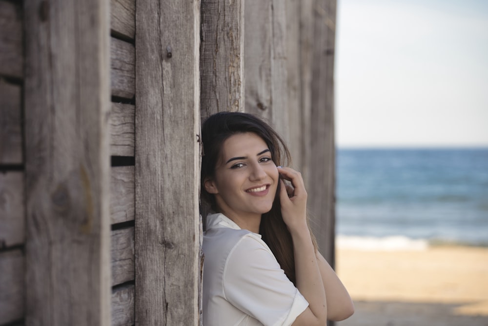 woman in white shirt leaning on brown wooden fence