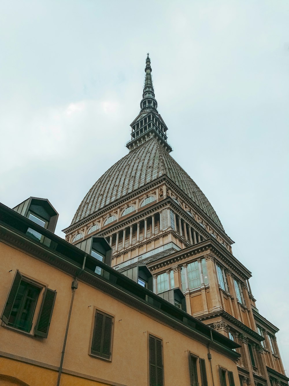 edificio in cemento marrone sotto il cielo bianco durante il giorno