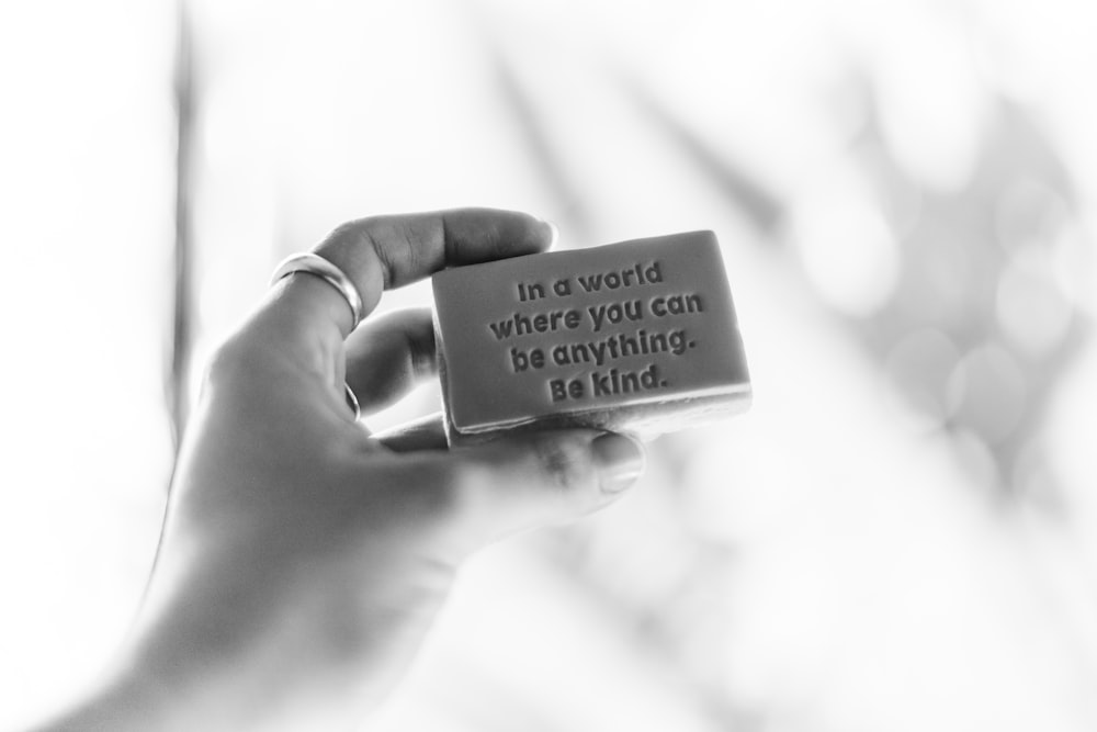 Foto in scala di grigi di una persona che tiene in mano una bacheca di citazioni