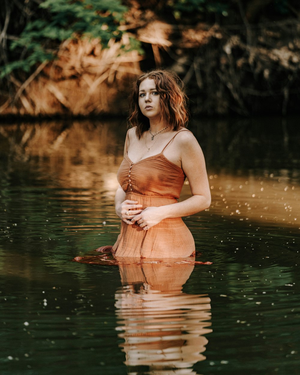 woman in white tank top and pink skirt standing on water during daytime