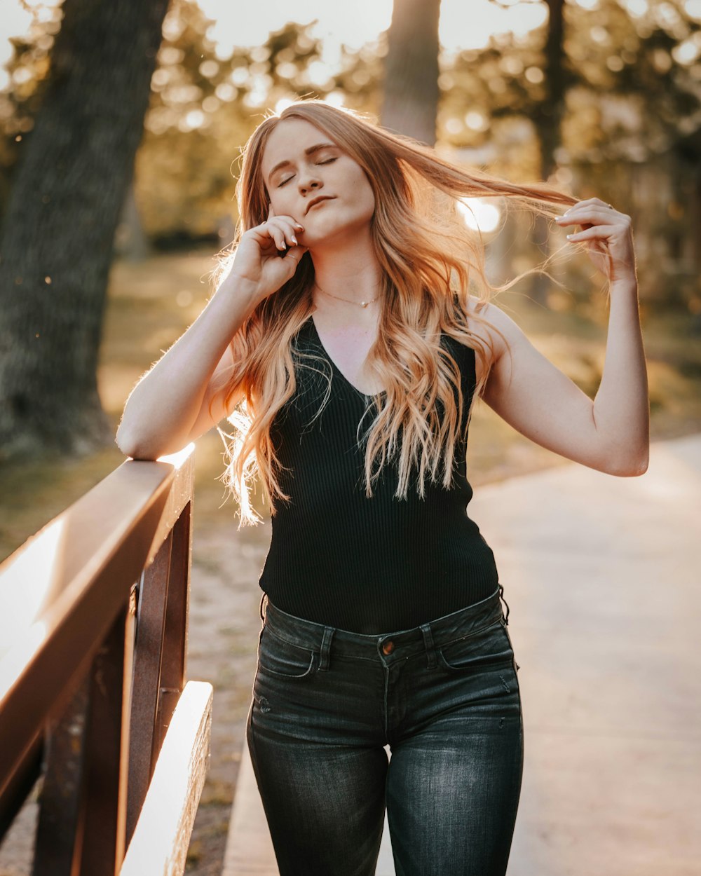 woman in black tank top and blue denim jeans standing and smiling