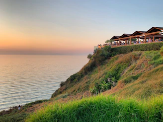 A panoramic view of a landscaped terrace overlooking Alanya's coastline at sunset.