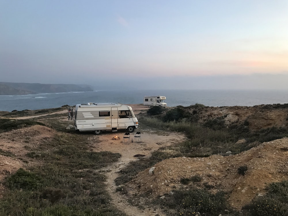Camping-car blanc et brun sur un terrain brun sous un ciel bleu pendant la journée