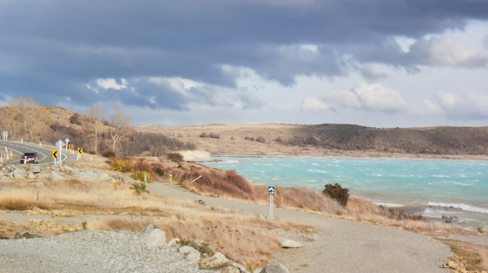 personne debout sur du sable brun près d’un plan d’eau pendant la journée