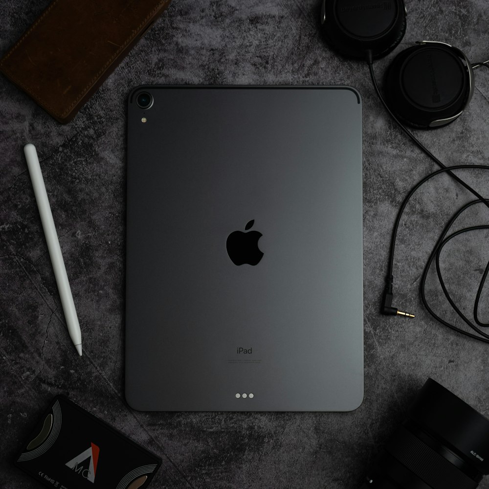 silver ipad beside black headphones